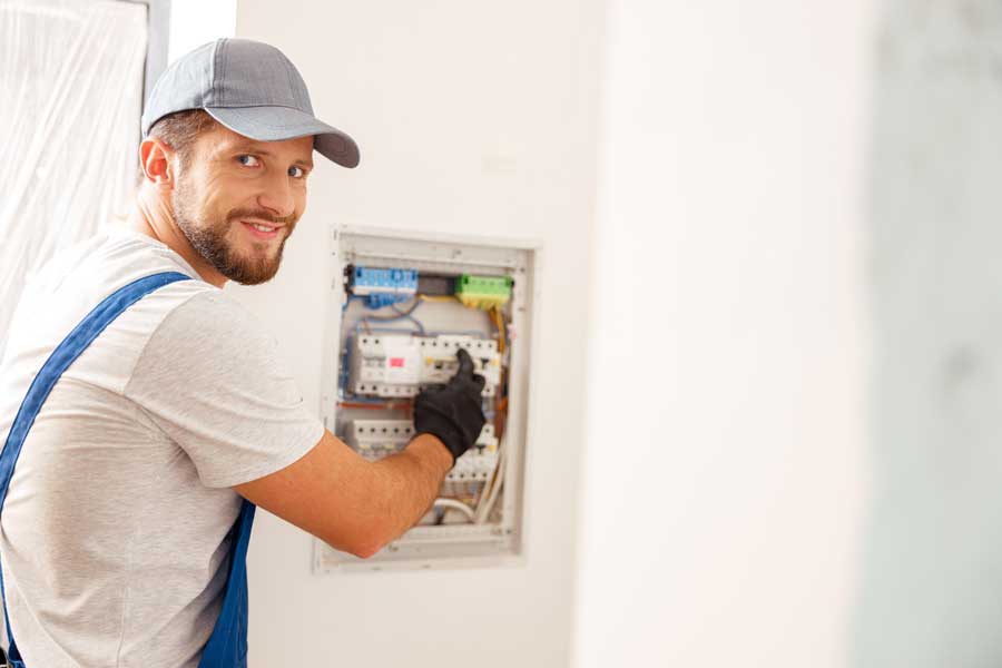 nettside_elektriker En smilende elektriker jobber i sikringsskapet.